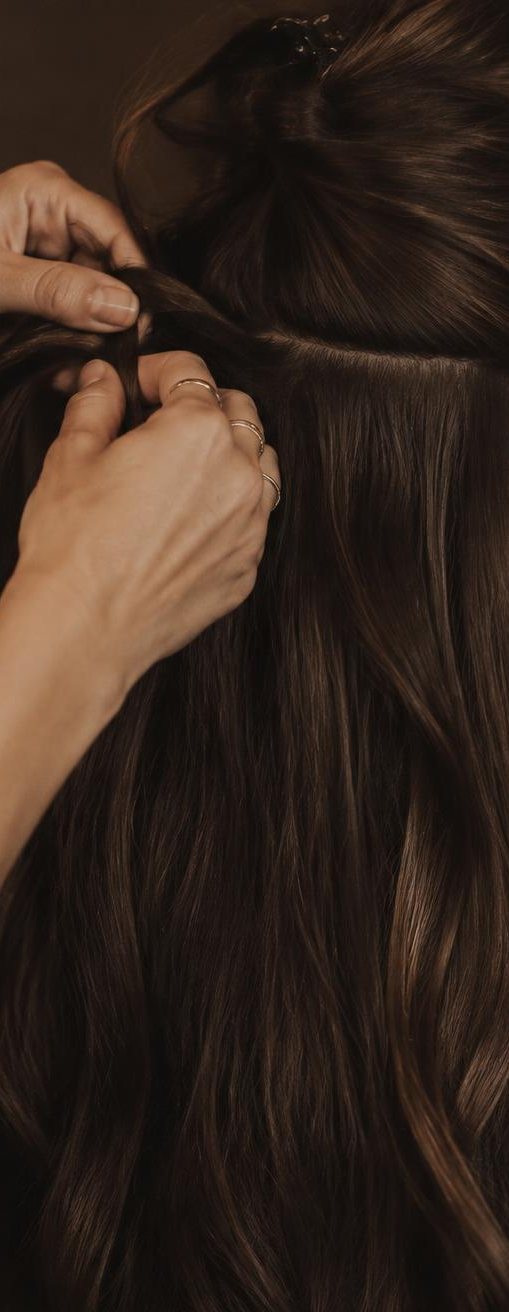 Hands carefully placing a hair extension at the root